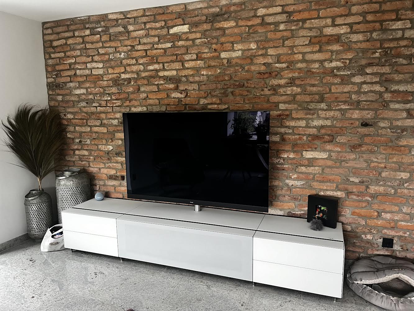 Stilvolles Wohnzimmer mit moderner TV-Wand vor einer Ziegelverkleidung aus recycelten Altziegeln – ein Mix aus Industrielook und klarer Raumgestaltung
