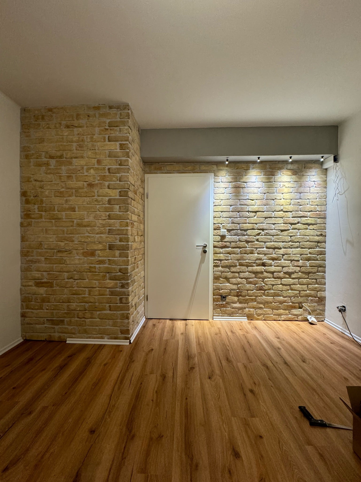 Moderner Innenraum mit einer Kombination aus freistehender Mauerstruktur und beleuchteter Verblendung aus handgefertigten Riemchen in Sandsteinoptik – perfekte Akzentwand für individuelle Raumgestaltung