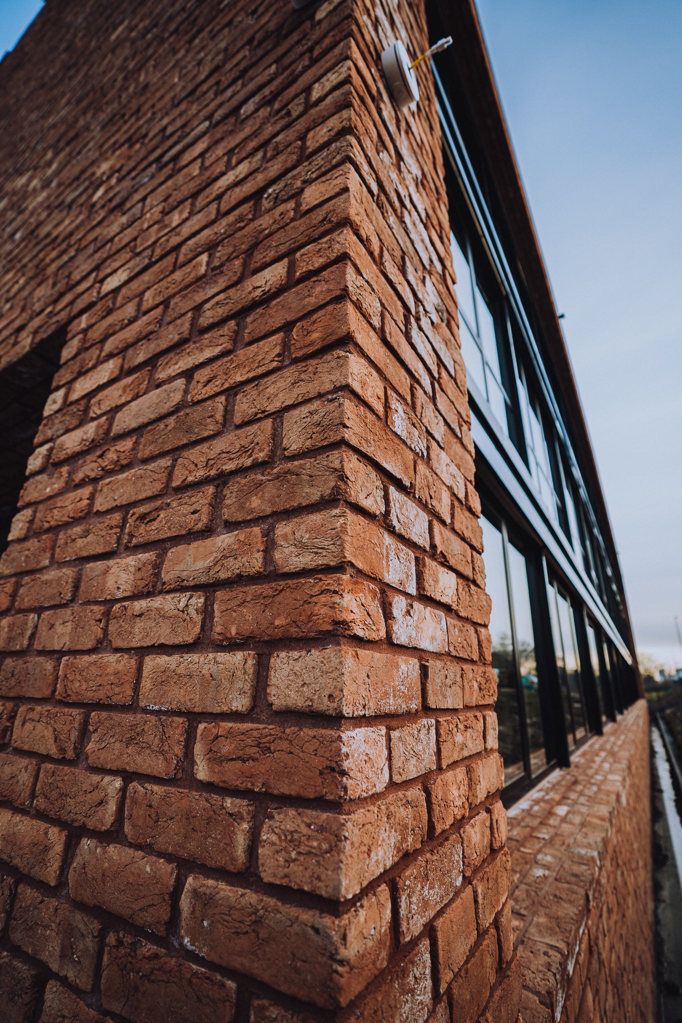 Moderne Gewerbefassade mit charakterstarken handgeformten Ziegelriemchen – Kombination aus Industrial Design und traditionellem Mauerwerk